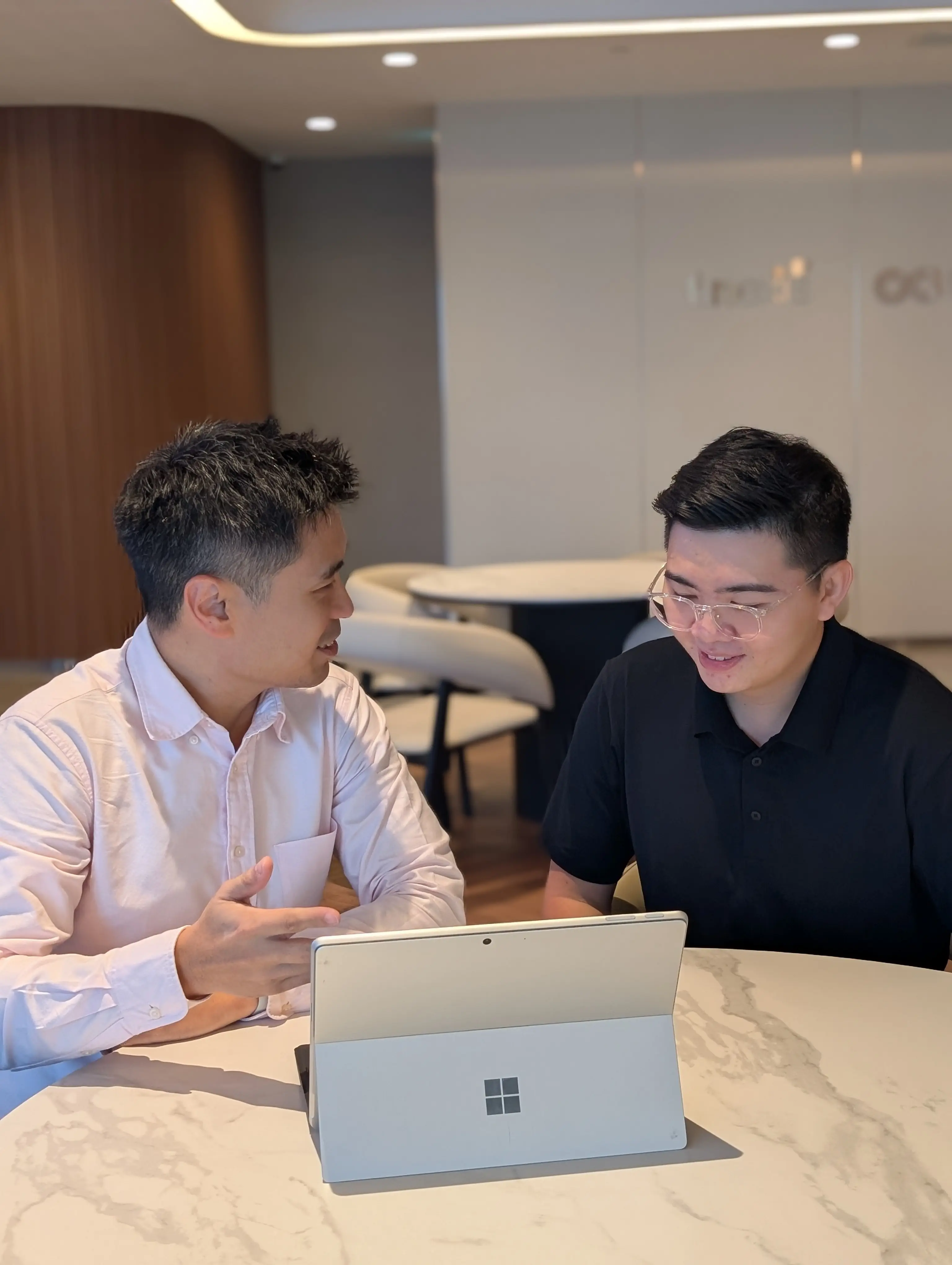 Ling Chun Wei talking through a plan with someone across a table at the finexis Advisory office